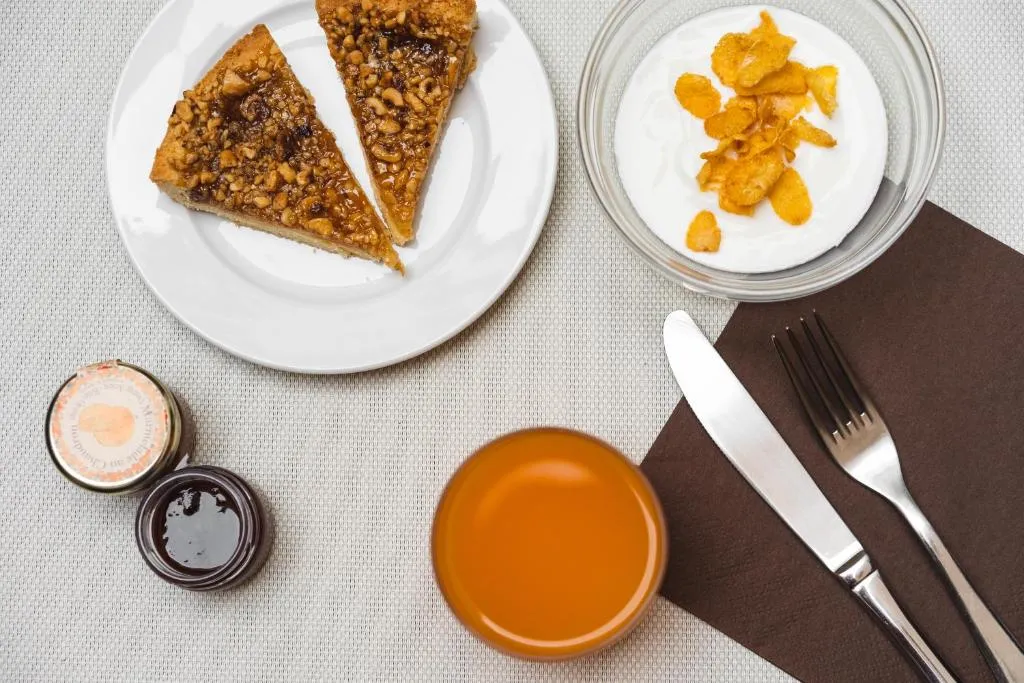 Colazione con torte, yogurt con cereali, marmellate e succo d'arancia