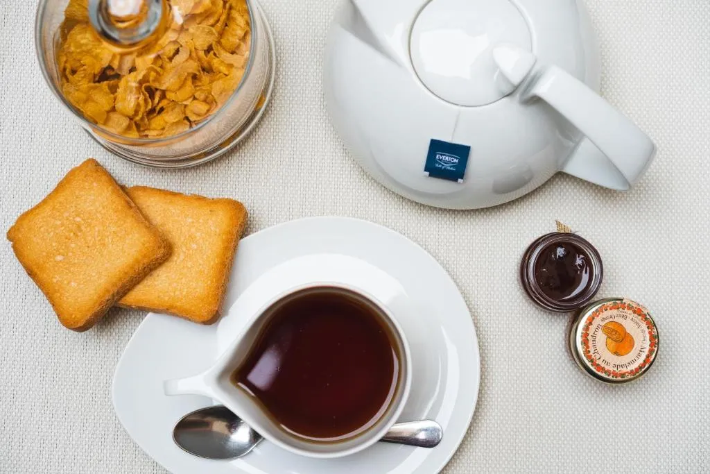 Colazione con tè, fette biscottate, cereali e marmellata