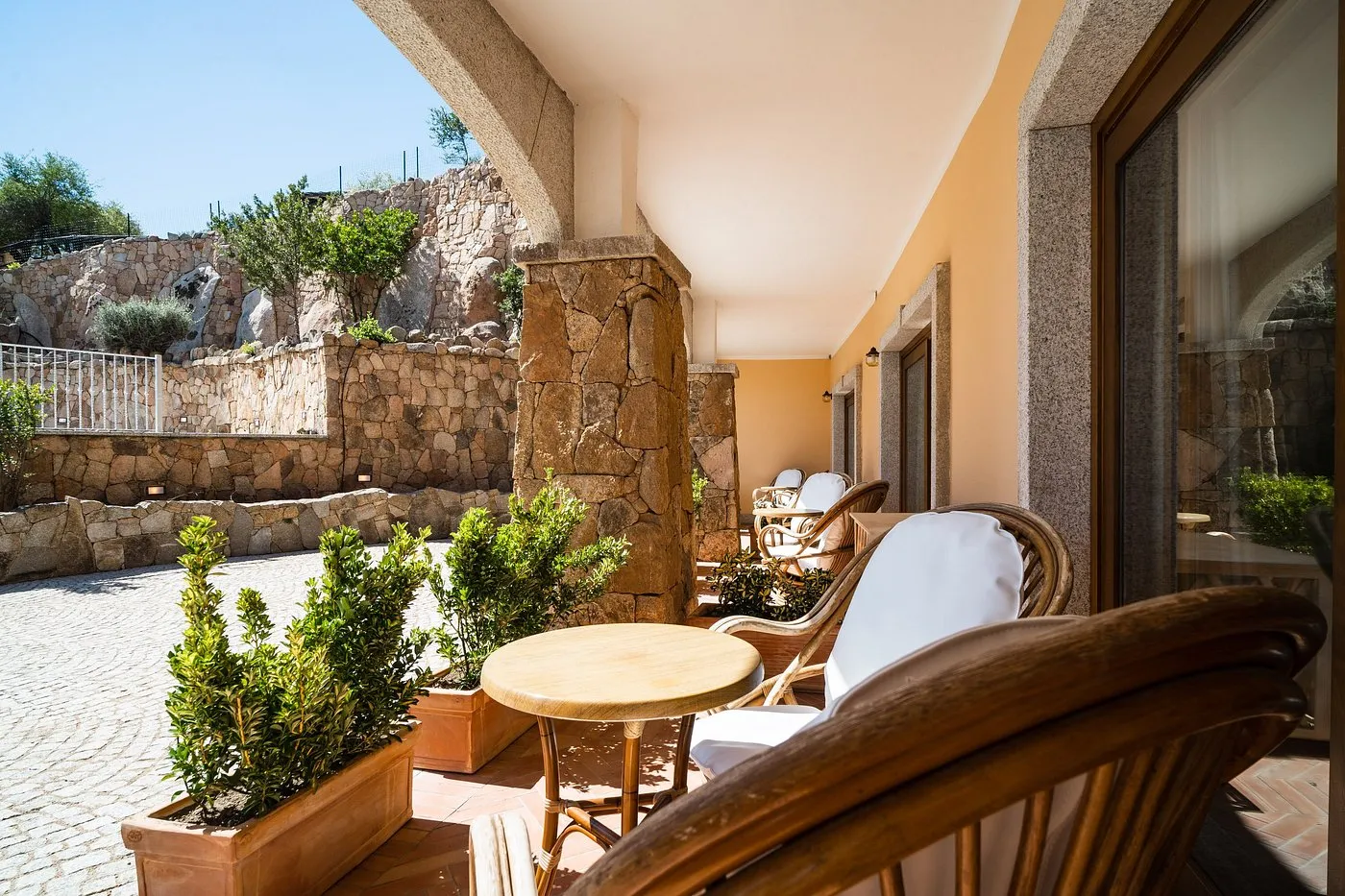 Terrazza privata della camera con poltrone in vimini e muro in pietra