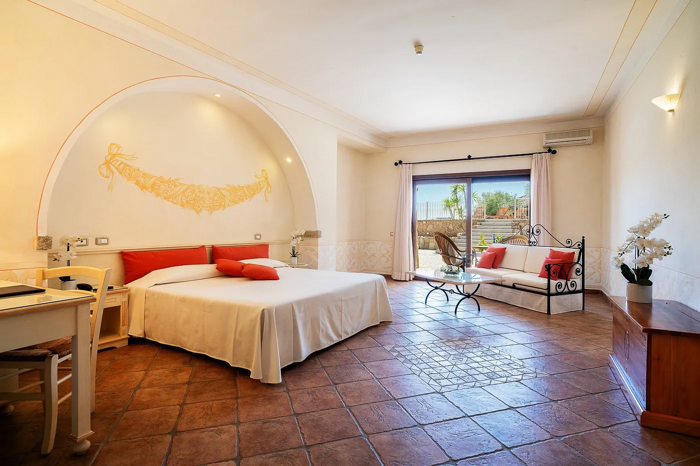 Ampia camera con letto matrimoniale, divano e uscita sul giardino