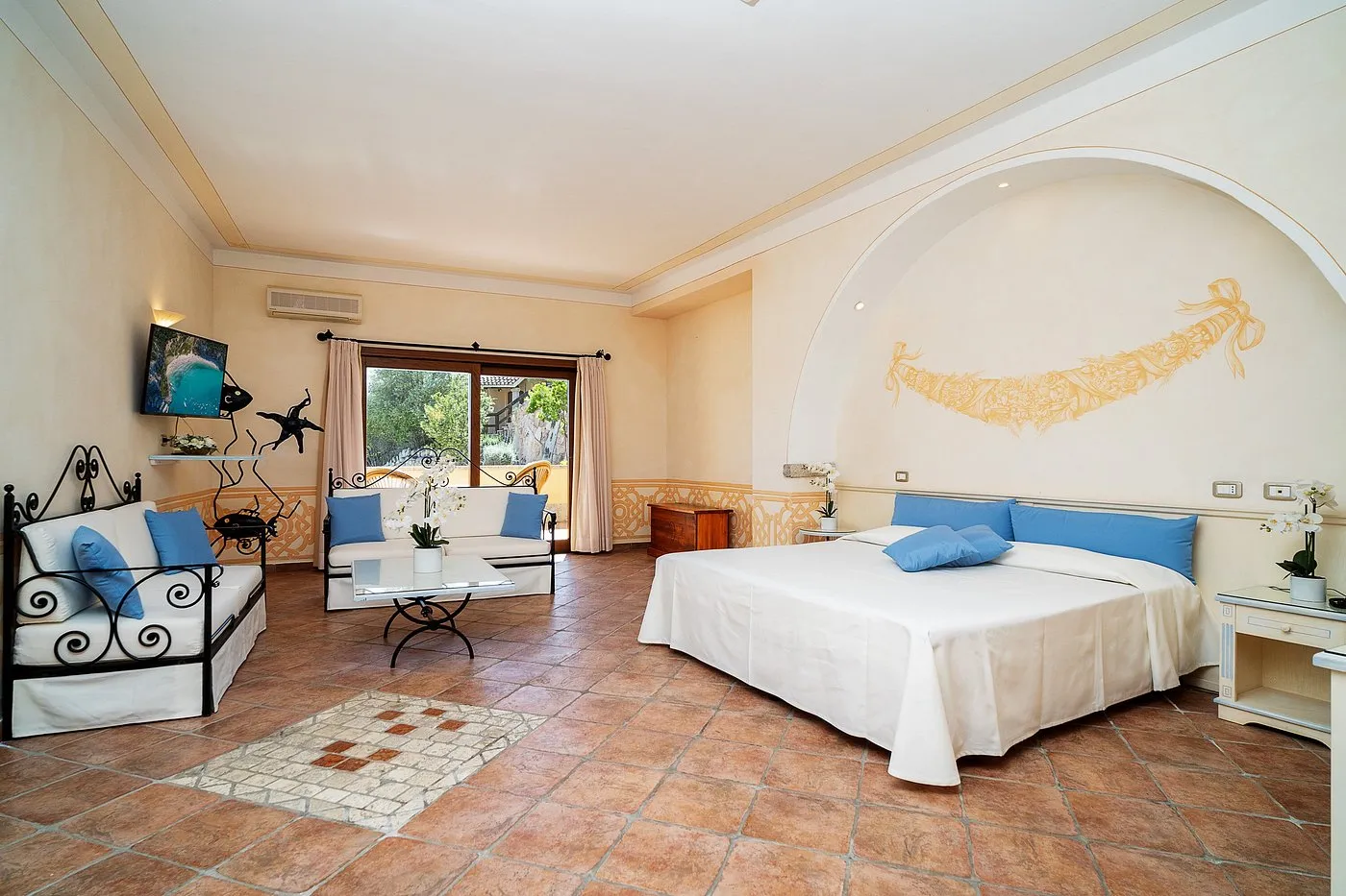 Spaziosa suite con letto, divani con cuscini azzurri e zona soggiorno