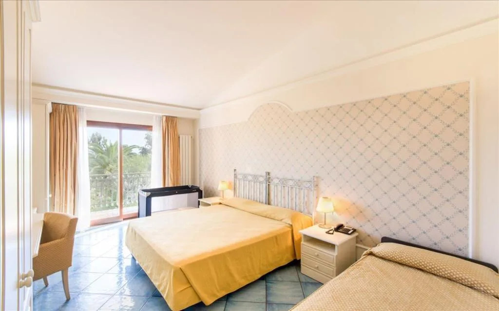 Camera tripla con letto matrimoniale e letto singolo, copriletto giallo e balcone con vista sul verde
