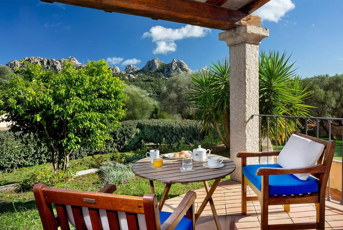 Terrazza con colazione servita su tavolino e vista sulle montagne e giardino