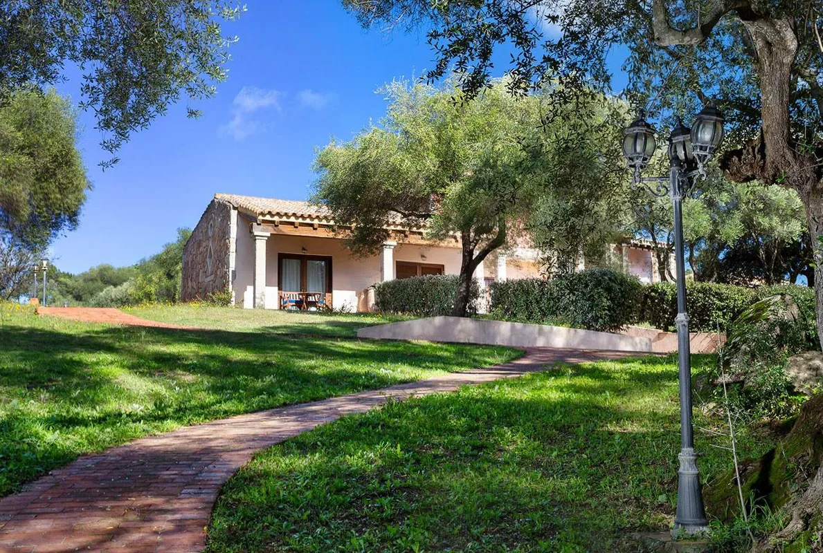 Villetta in pietra con portico circondata da prato verde e vialetto in mattoni