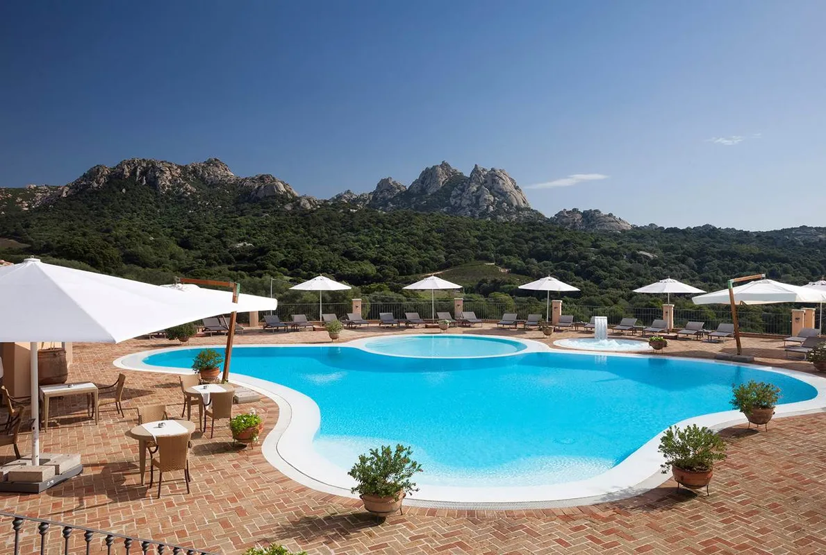 Piscina a forma libera con ombrelloni e lettini, vista sulle montagne