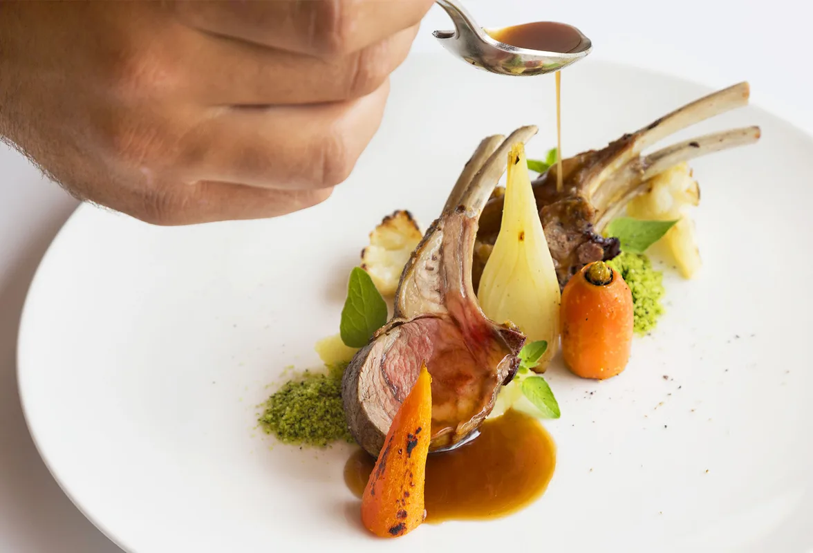 Costoletta di agnello con verdure e salsa impiattata da chef