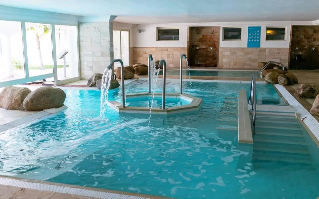 Piscina coperta termale con getti d'acqua e rocce decorative