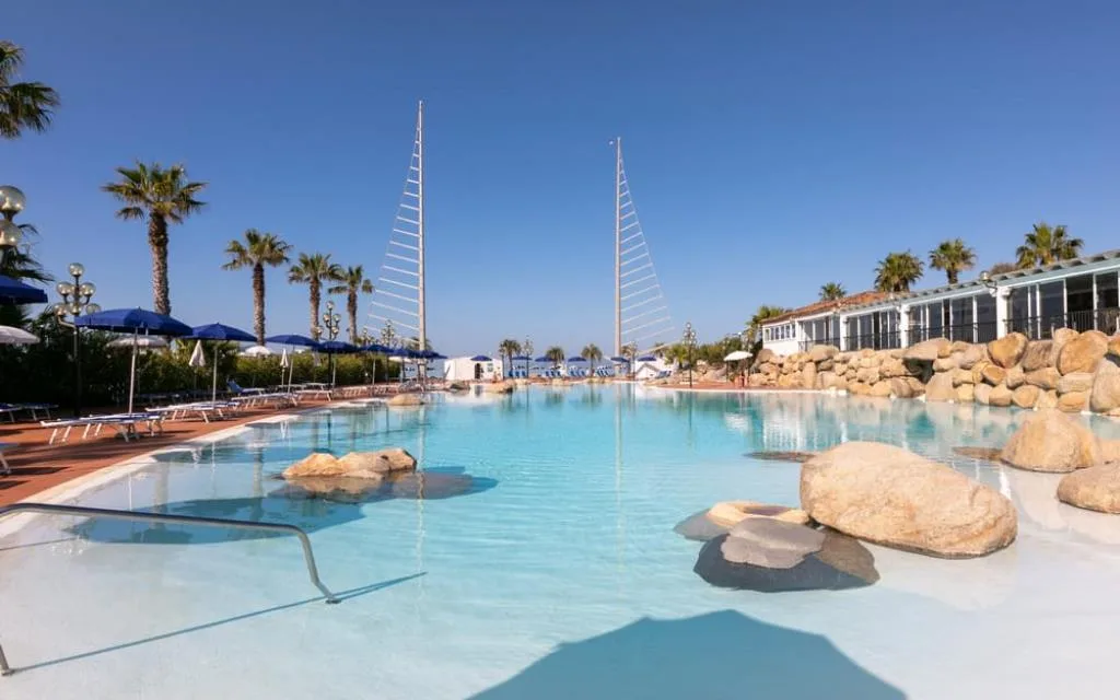 Piscina con rocce e vele decorative vista mare e lettini