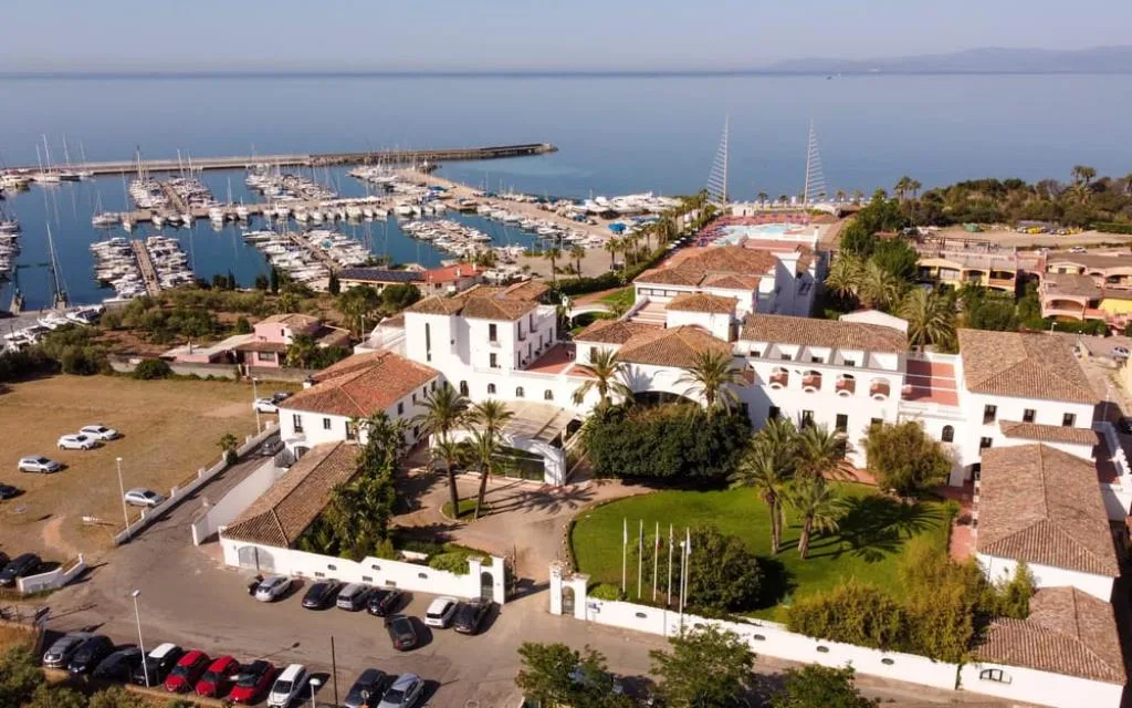 Vista aerea del resort bianco con tetti in cotto accanto al porto turistico
