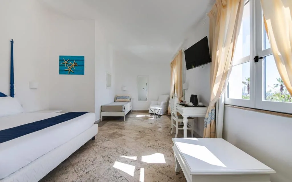 Camera luminosa bianca con letto matrimoniale, letto singolo e pavimento in marmo