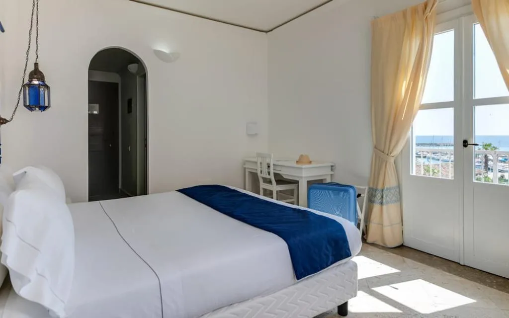 Camera bianca con letto, scrivania e finestra vista porto