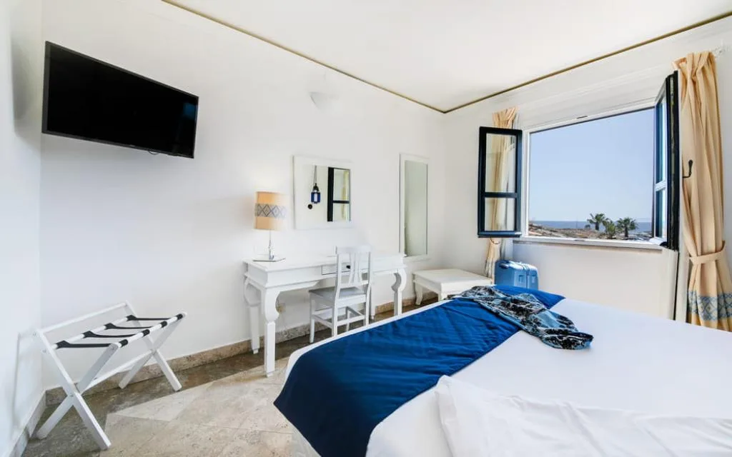 Camera luminosa con letto, TV a parete e finestra vista mare