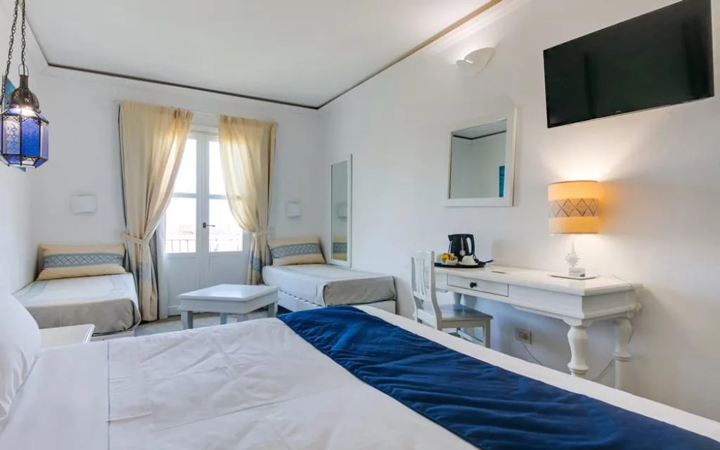 Camera tripla con letto matrimoniale, letti singoli e scrivania bianca