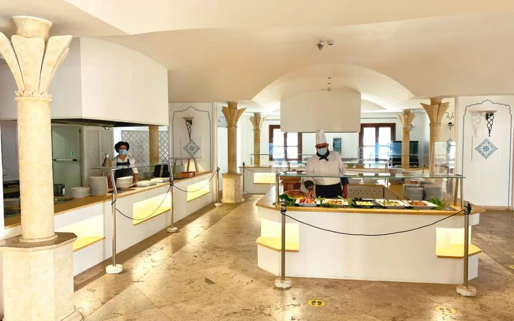 Area buffet del ristorante con colonne decorate e personale al lavoro