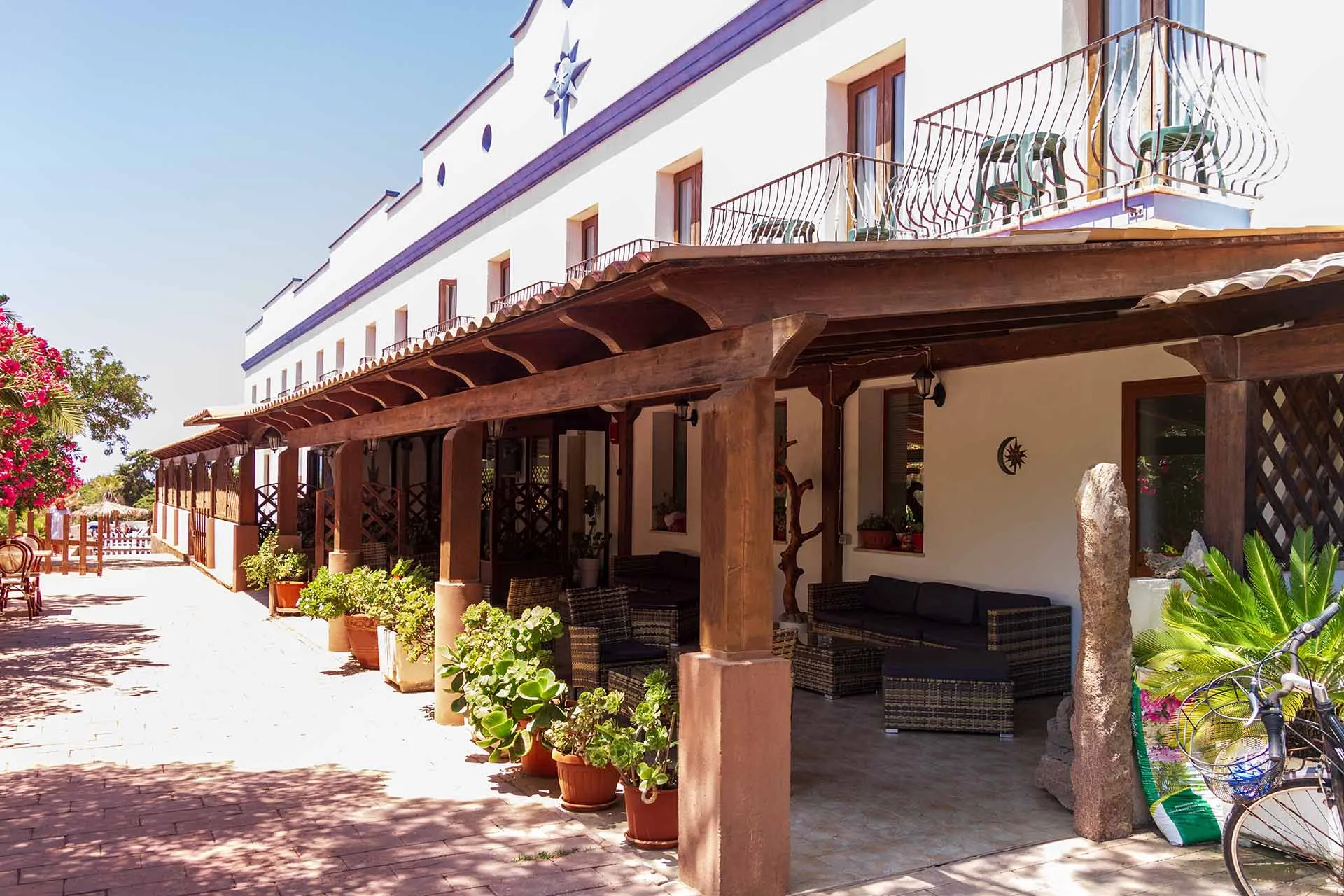 Veranda esterna dell'hotel con pergolato in legno, divani e piante