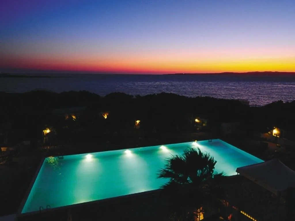 Piscina illuminata al tramonto con vista sul mare