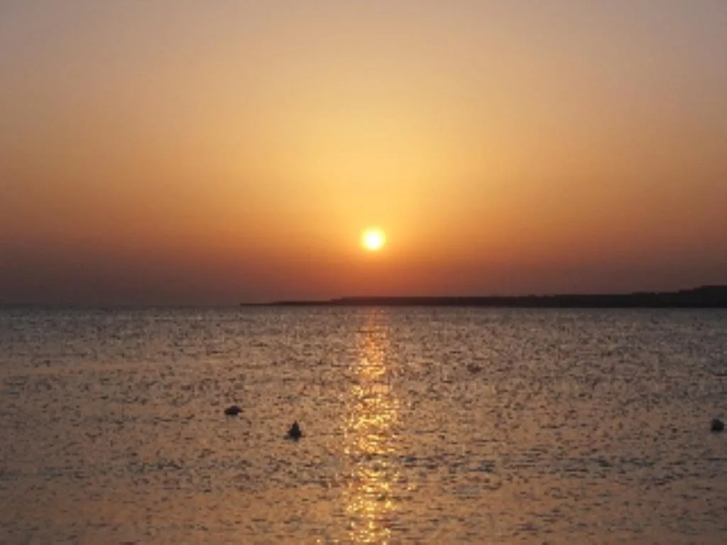 Tramonto sul mare con sole riflesso sull'acqua