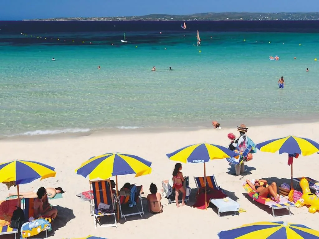 Spiaggia con ombrelloni colorati e mare turchese affollato di bagnanti
