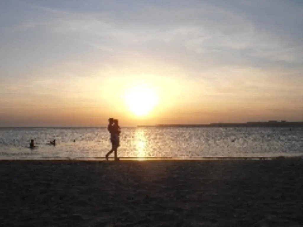 Silhouette di persona che cammina sulla spiaggia al tramonto