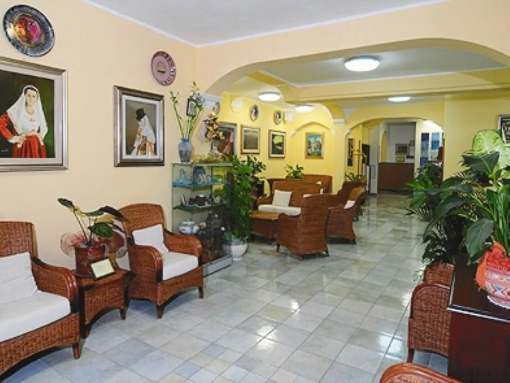 Hall dell'hotel con poltrone in vimini, piante e quadri alle pareti