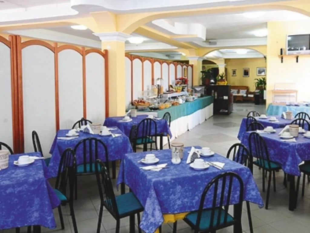 Sala ristorante con tavoli apparecchiati con tovaglie blu e buffet