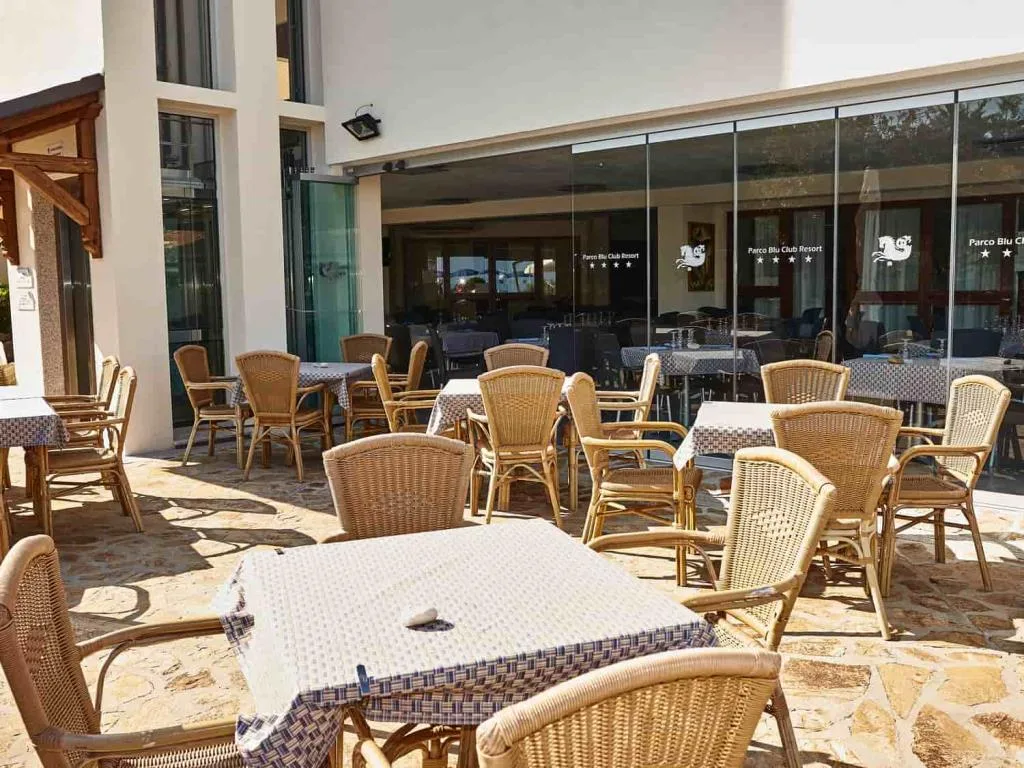 Terrazza esterna del ristorante con tavoli e sedie in vimini su pavimento in pietra