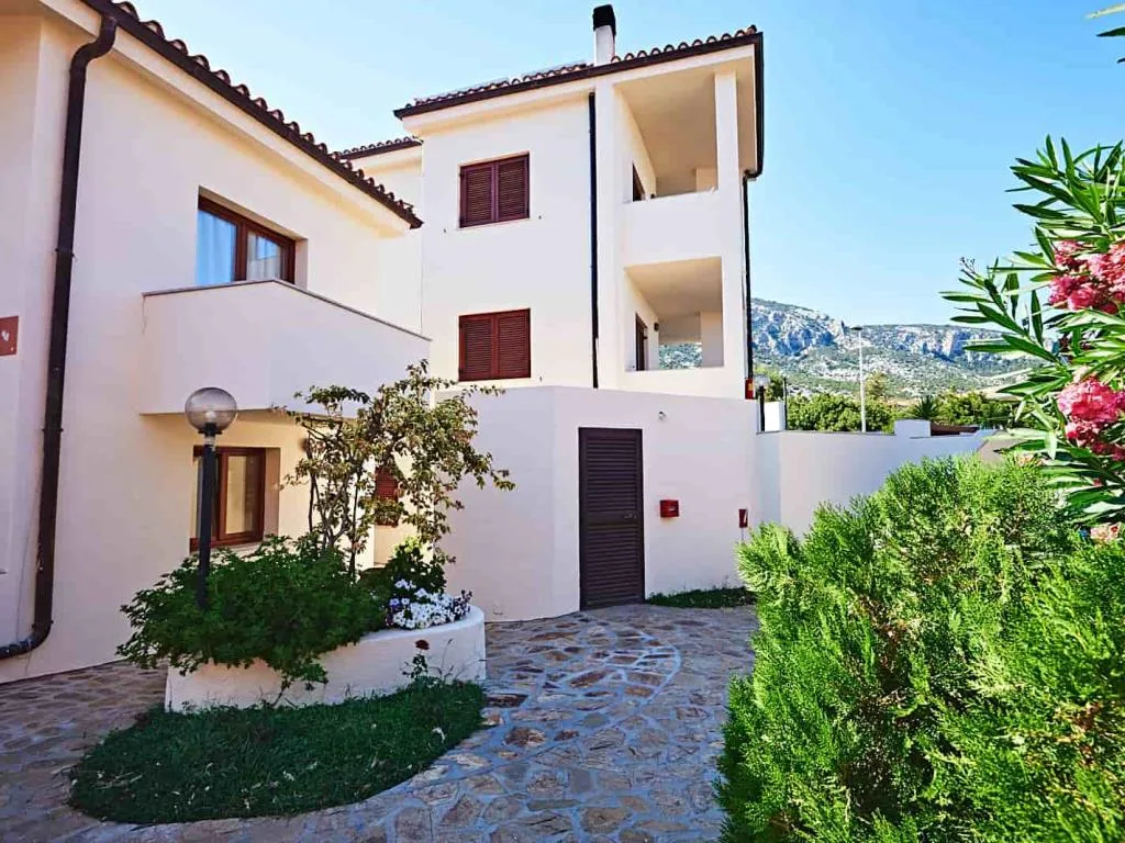 Edificio bianco dell'hotel con giardino curato e montagne sullo sfondo