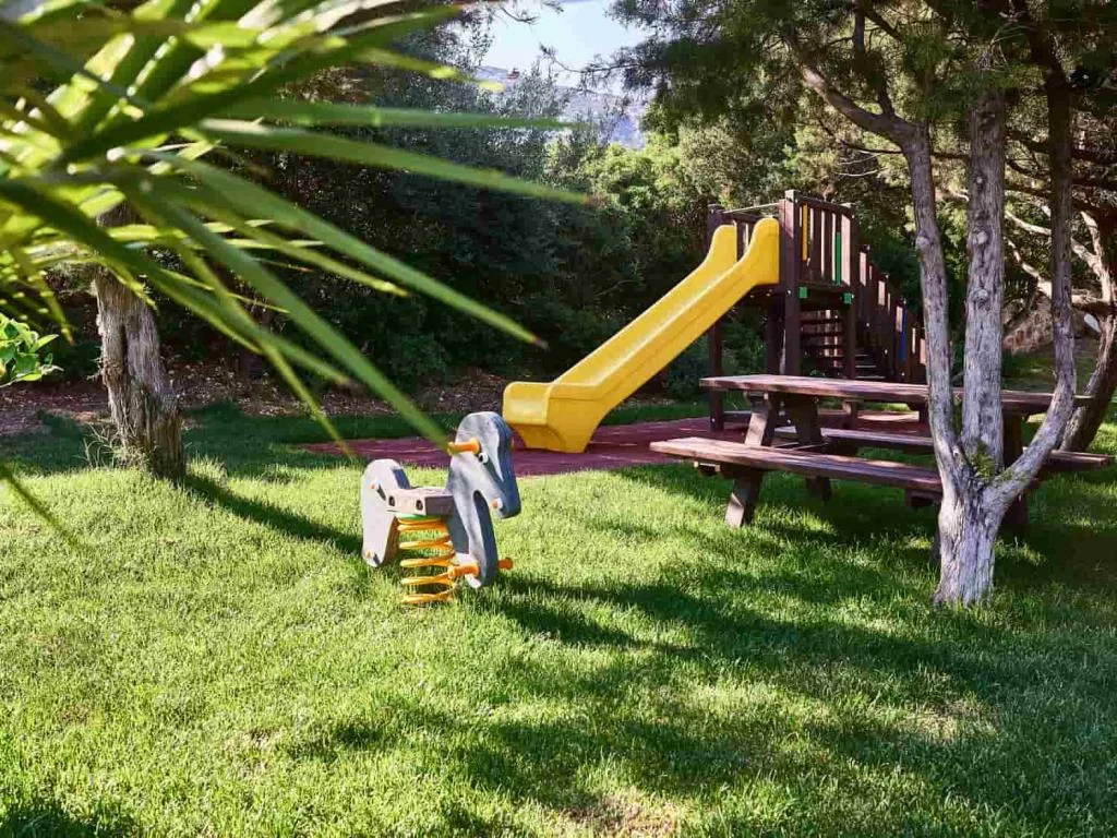 Area giochi per bambini nel giardino con scivolo giallo e tavolo da picnic