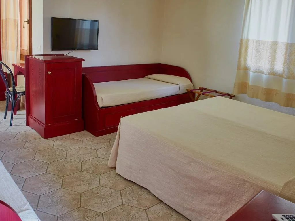 Camera con letto matrimoniale, divano letto singolo rosso e TV a parete