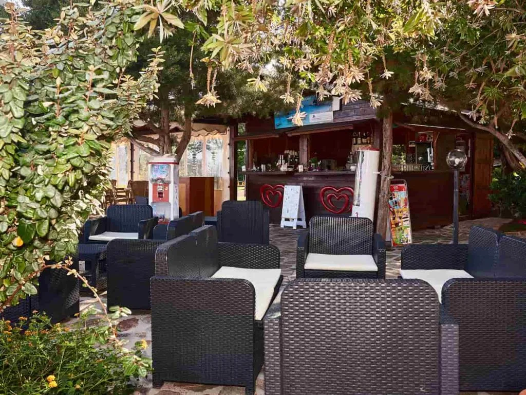 Bar all'aperto immerso nel verde con poltrone in vimini e decorazioni a cuore