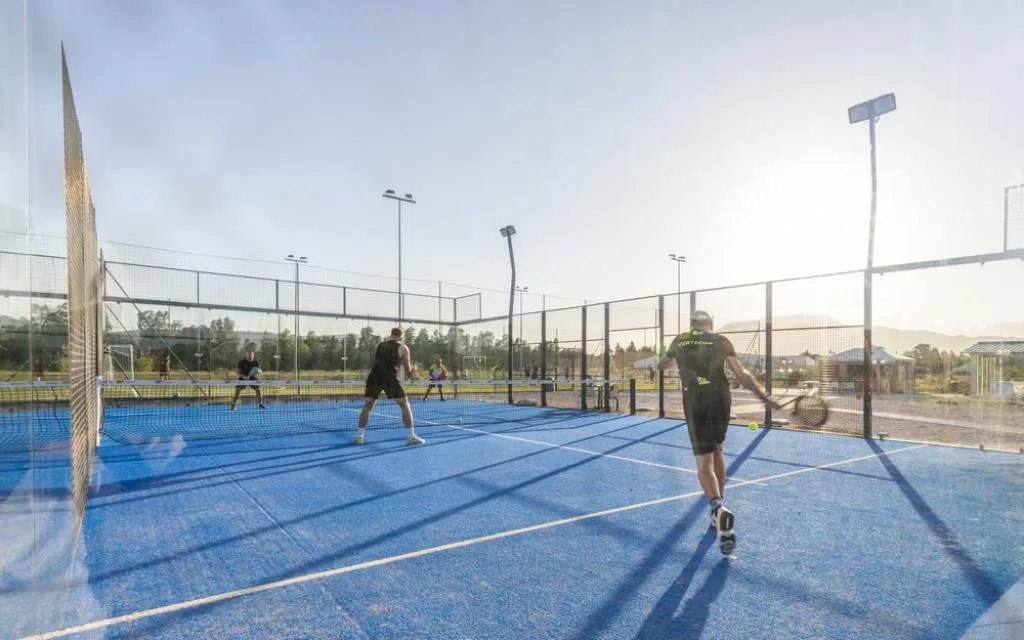 Partita di padel su campo blu illuminato al tramonto
