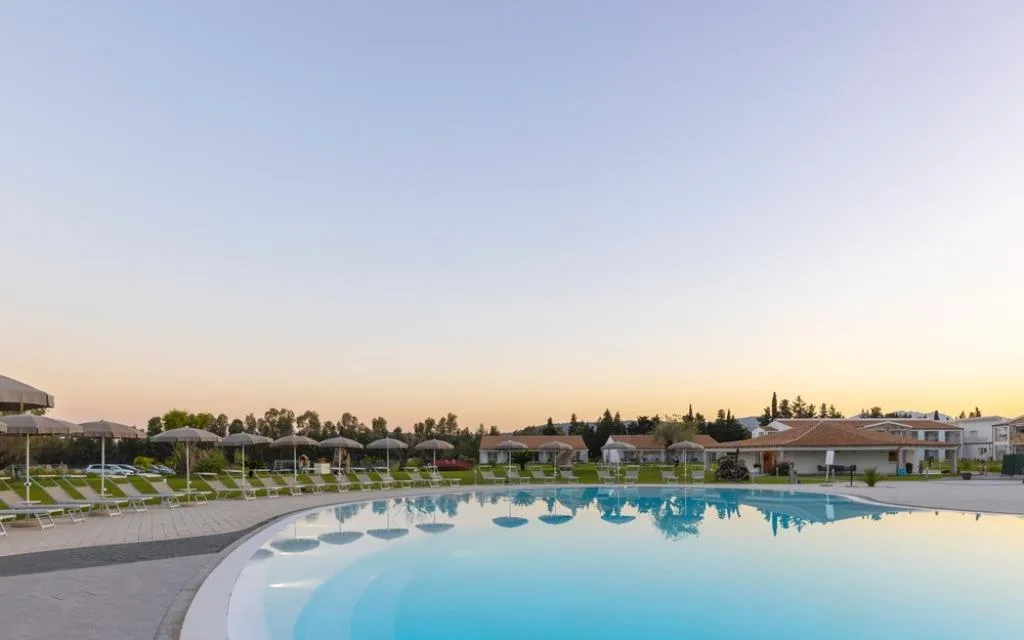 Piscina del resort con ombrelloni e lettini al tramonto