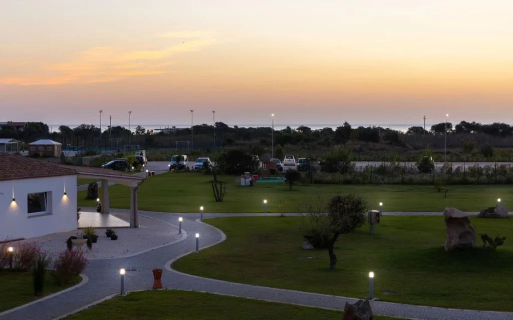 Giardino del resort illuminato al tramonto con vista sul mare