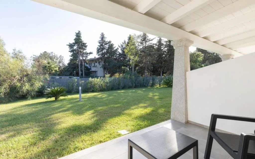 Veranda privata con tavolino e vista sul giardino verde