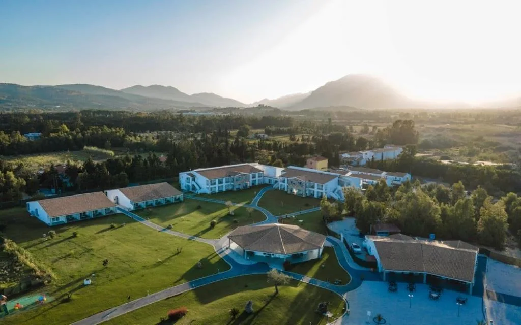 Veduta aerea del resort immerso nel verde con montagne sullo sfondo