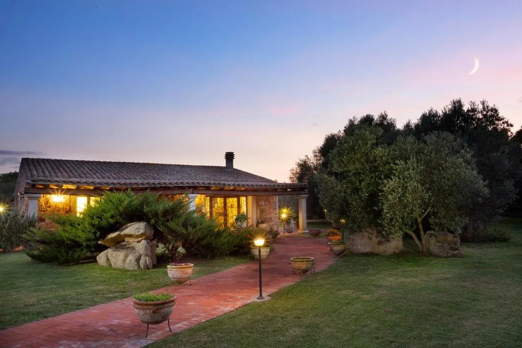 Edificio in pietra illuminato al tramonto con giardino e ulivi