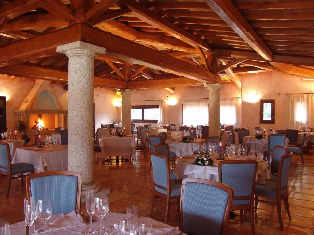 Sala ristorante interna con travi in legno, colonne e camino acceso