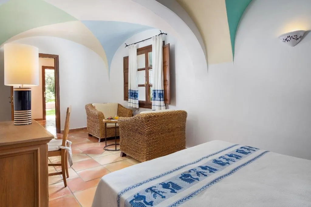 Camera con letto, poltrone in vimini e soffitto a volta dipinto