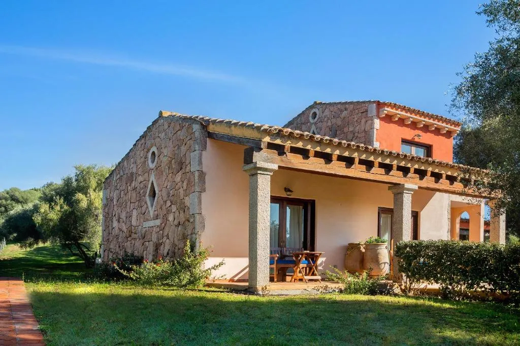 Casetta in pietra con portico e colonne immersa nel verde