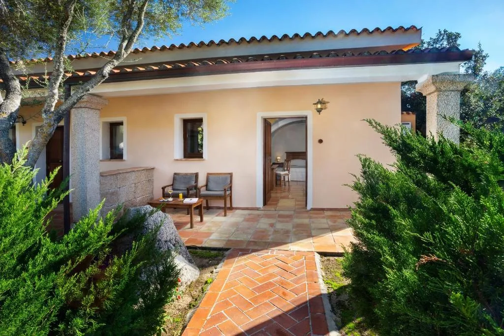 Casetta con portico, poltrone e ingresso immersa nella vegetazione