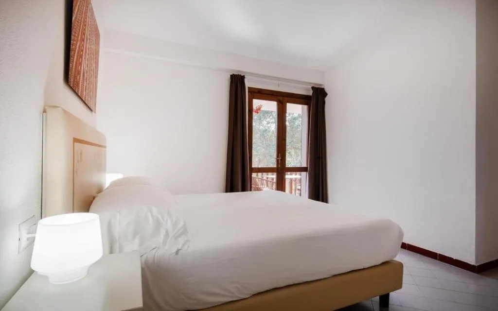 Camera matrimoniale con letto bianco e finestra sul balcone