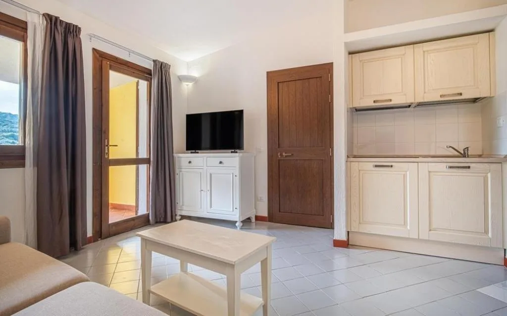 Soggiorno con angolo cottura, TV e accesso al balcone