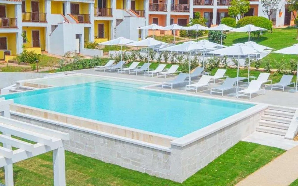 Piscina del resort con lettini bianchi e ombrelloni