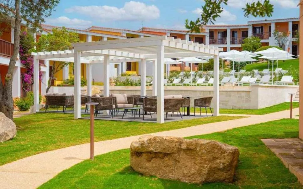 Gazebo bianco con divani e poltrone nel giardino vicino alla piscina