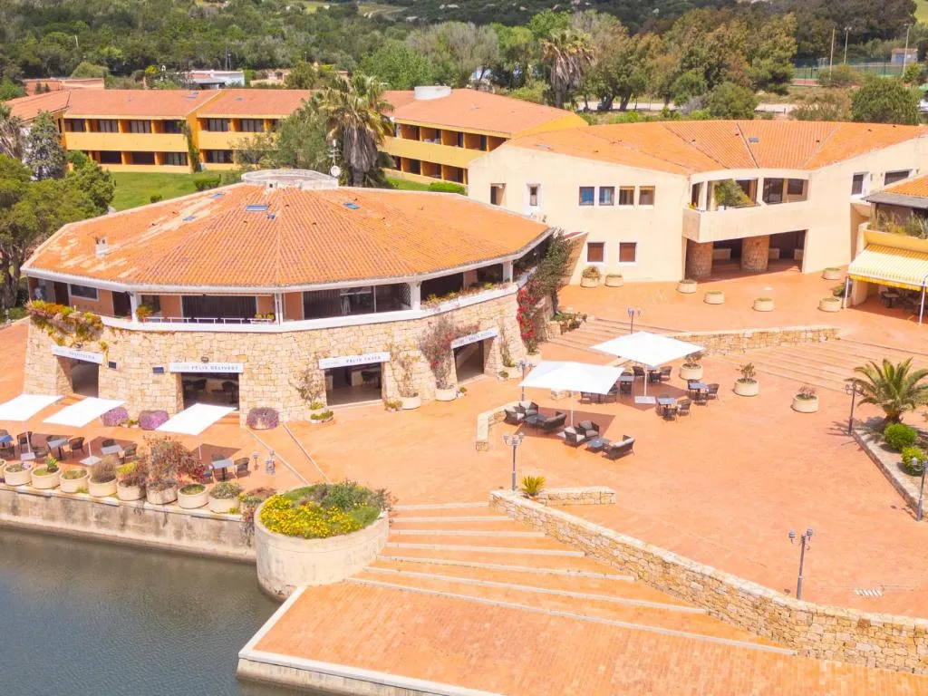 Vista aerea dell'edificio principale in pietra del resort con terrazza, ombrelloni e affaccio sull'acqua