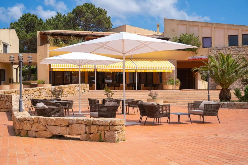 Terrazza esterna con ombrelloni, tavoli e poltrone in vimini davanti al bistrot del resort