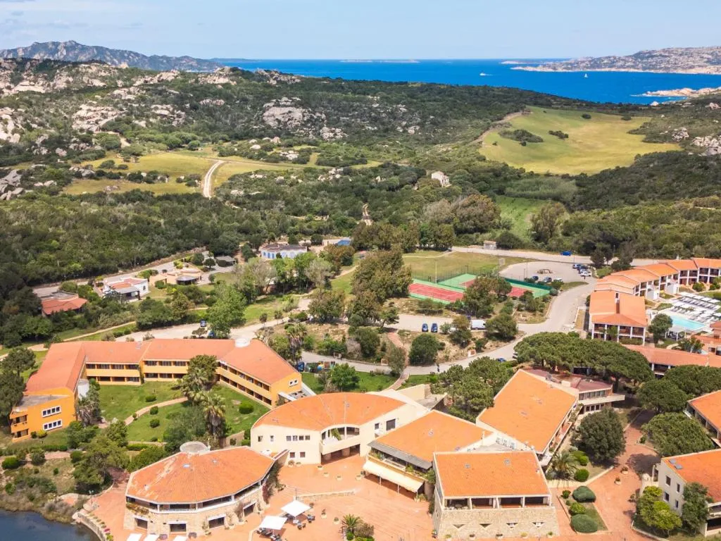 Panorama aereo del resort immerso nella macchia mediterranea con il mare blu sullo sfondo