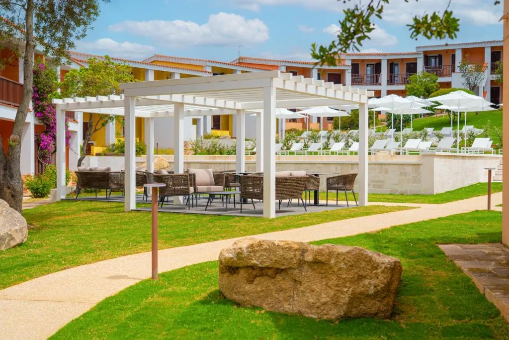 Pergola bianca con divani e poltrone in vimini nel giardino del resort vicino alla zona piscina