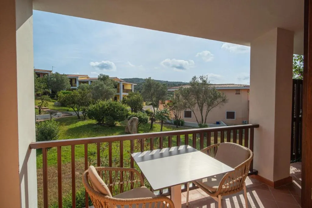 Balcone con tavolino e sedie affacciato sul giardino verde e gli edifici del resort