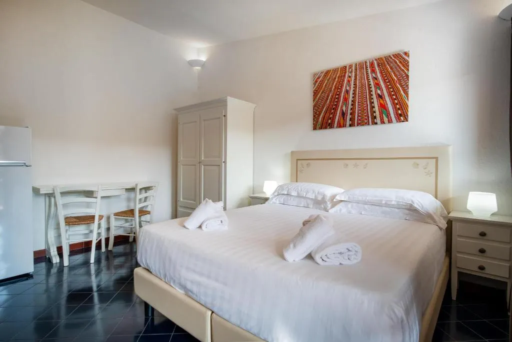 Monolocale con letto matrimoniale, angolo cottura, tavolo e pavimento scuro